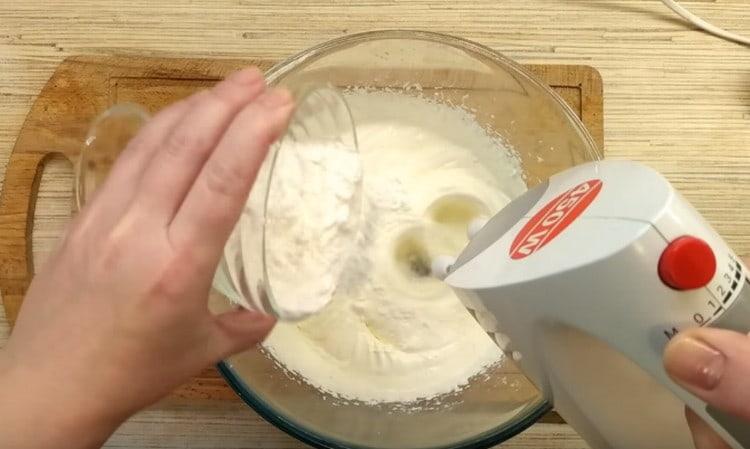 Į grietinę įpilkite krakmolo ir miltelinio cukraus mišinio.