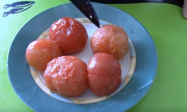 Gießen Sie die Tomaten mit kochendem Wasser und entfernen Sie die Haut von ihnen.