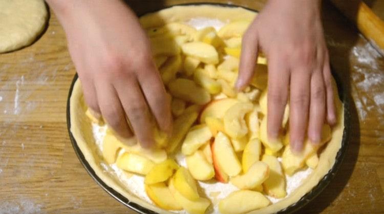 Разстелете нарязани на филийки ябълки и разпределете равномерно върху тестото.