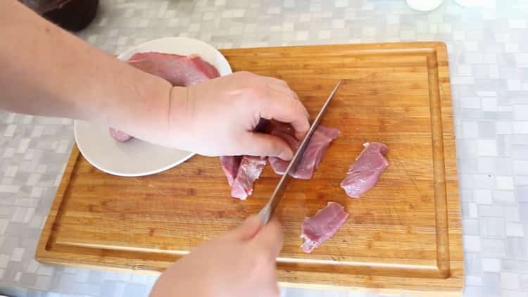 Zum Kochen von Rindfleisch in Töpfen mit Kartoffeln im Ofen das Fleisch hacken