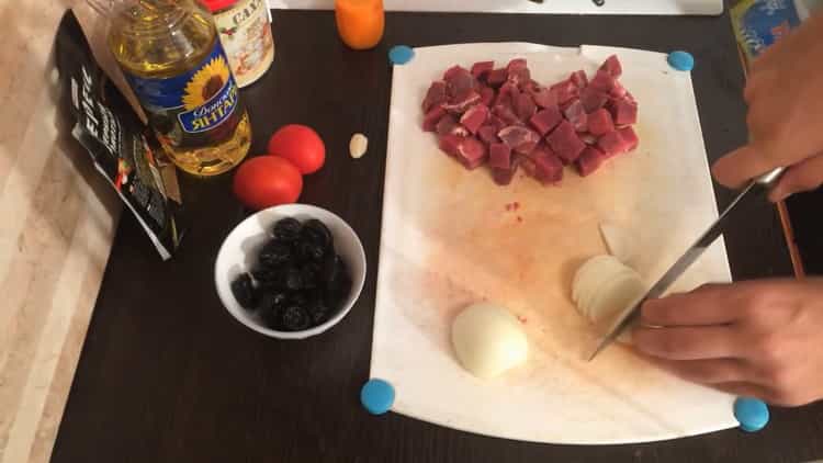 Per cucinare lo stufato di manzo con le prugne secche, tagliare la cipolla