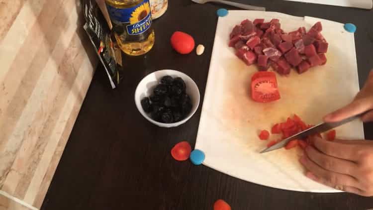 Zum Kochen von Rindfleischeintopf mit Zwetschgen die Tomate hacken