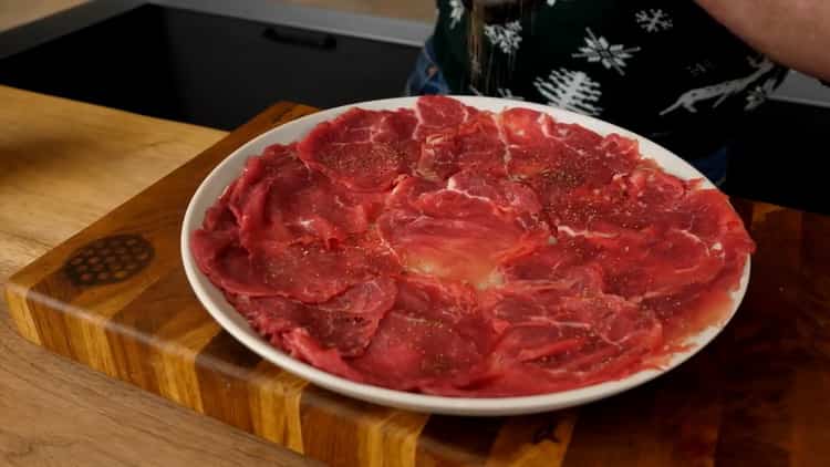 Um Carpaccio vom Rind zuzubereiten, legen Sie das Fleisch in einen Teller