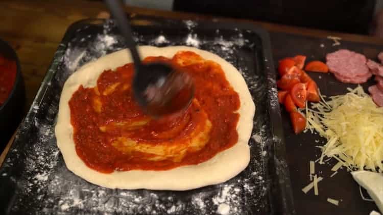 Für eine klassische Pizza den Teig mit Sauce einfetten