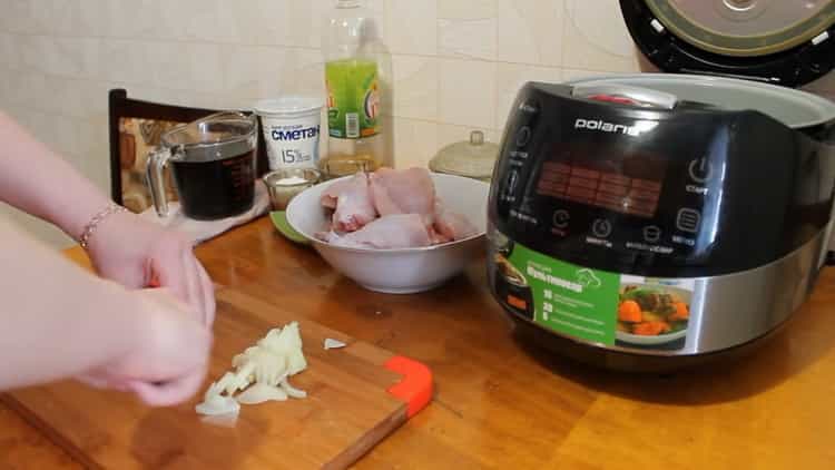 Hacken Sie die Zwiebel, um ein Kaninchen in einem Slow Cooker in einer Sauce aus saurer Sahne zu kochen