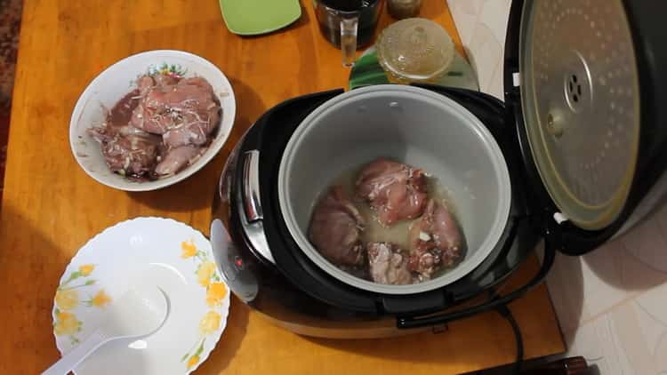 Braten Sie das Fleisch an, um ein Kaninchen in einem Slow Cooker in einer Sauce aus saurer Sahne zu kochen