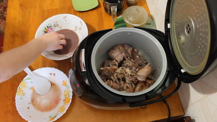 Braten Sie die Zwiebeln, um ein Kaninchen in einem Slow Cooker in einer Sauce aus saurer Sahne zu kochen