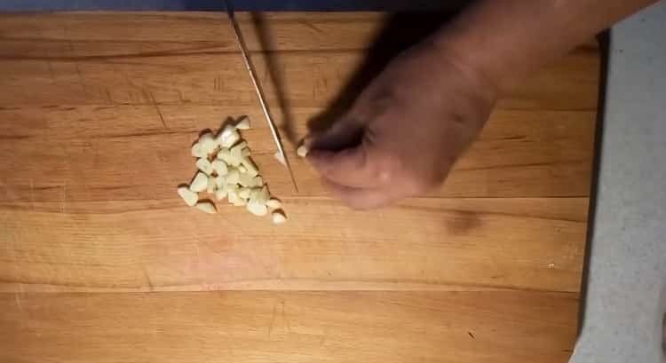Per cuocere un coniglio in panna acida nel forno, tritare l'aglio