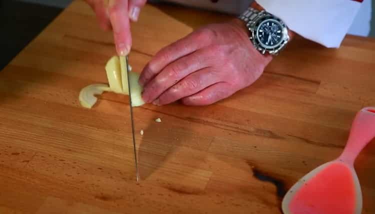 Per cuocere un coniglio con patate in una pentola a cottura lenta, tagliare la cipolla