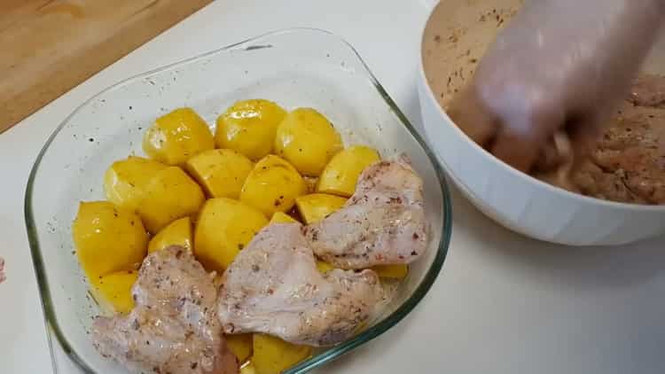 Um Hähnchenflügel mit Kartoffeln im Ofen zuzubereiten, legen Sie das Fleisch auf die Kartoffeln