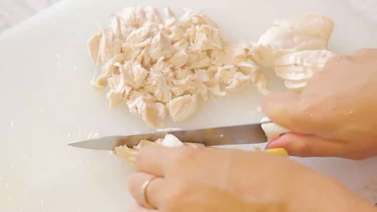 Hacken Sie das Fleisch, um eine Laurentianische Torte mit Hühnchen und Champignons zuzubereiten