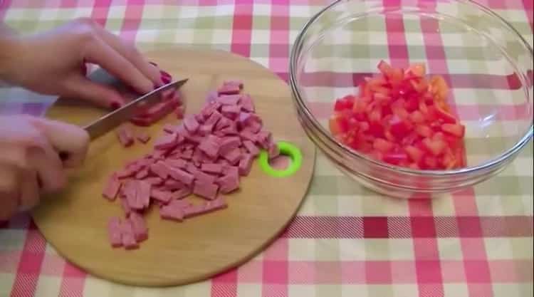 Schneiden Sie die Wurst, um eine Mini-Pizza auf einem Laib zuzubereiten