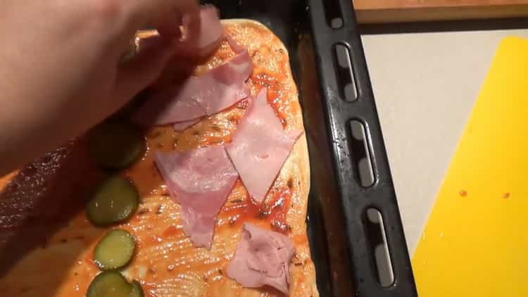 За да приготвите гарнитурата за пица, сложете шунката върху тестото