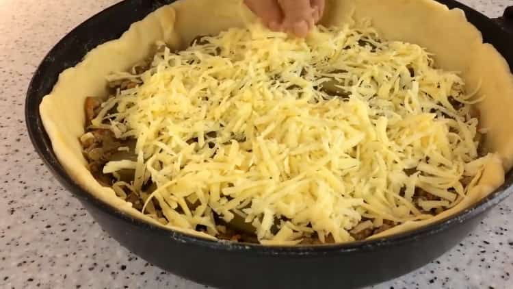 Um einen Kuchen in einer Pfanne zuzubereiten, bestreuen Sie die Füllung mit Käse