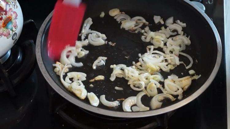 Braten Sie die Zwiebeln an, um eine Pilztorte im Ofen zuzubereiten