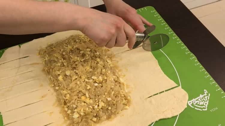 Um im Ofen einen Kuchen mit Kohl und Ei zuzubereiten, schneiden Sie den Teig ein