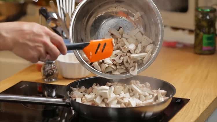 Csirkével és gombával történő pite készítéséhez adjunk hozzá gombát a serpenyőbe