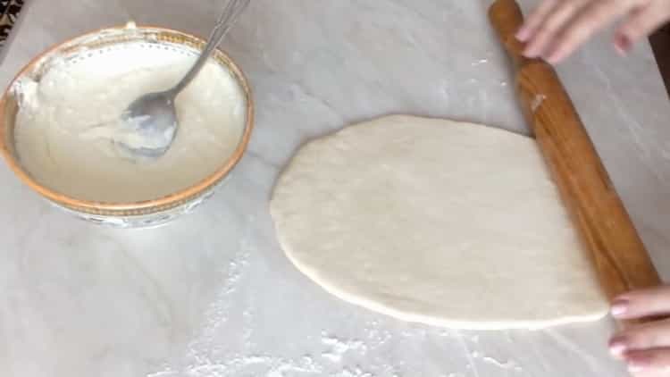 Rollen Sie den Teig aus, um einen Kuchen mit Hüttenkäse aus Hefeteig zuzubereiten