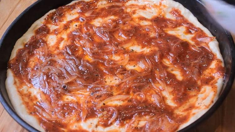 Vet het deeg in met een saus om pizza in de oven te maken