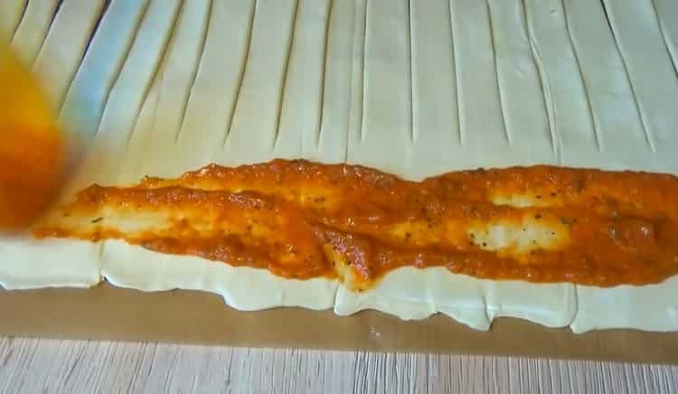 Per preparare la pizza dalla pasta sfoglia, metti il ​​ripieno sull'impasto
