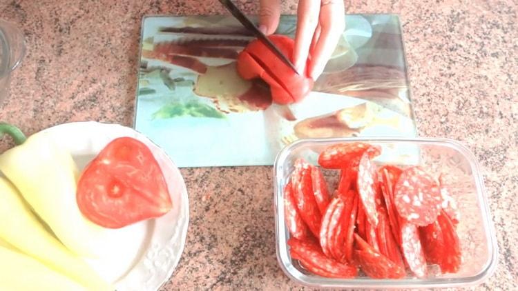 Hacken Sie die Tomaten, um im Ofen eine Blätterteigpizza zuzubereiten