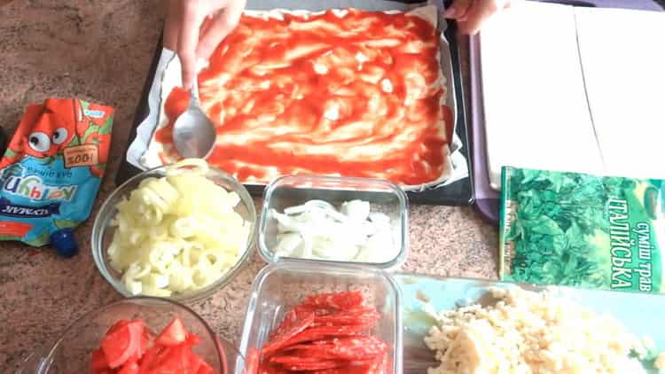 Fetten Sie den Teig mit Tomaten ein, um im Ofen eine Blätterteigpizza zuzubereiten