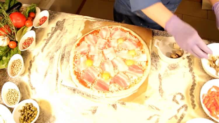 Eier auf den Teig legen, um Carbonara-Pizza zuzubereiten.