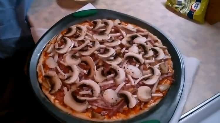 Pizza gombával és sajttal készítéséhez aprítsa el a gombát.