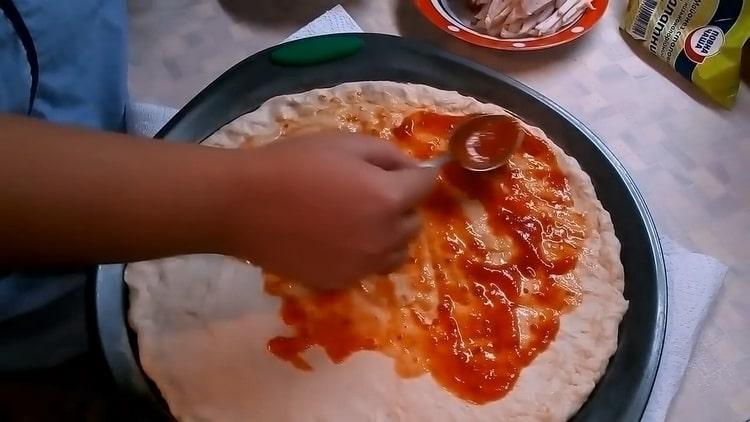 За да направите пица с гъби и сирене, намажете тестото със сос