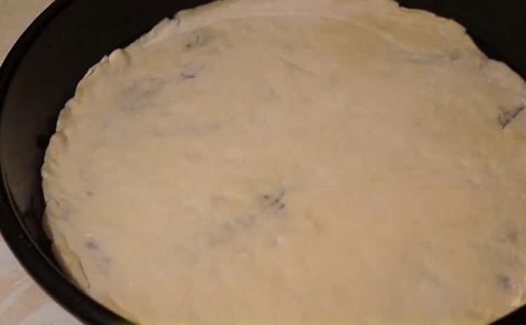 Um Pizza mit Wurst und Käse zuzubereiten, legen Sie den Teig in ein Backblech