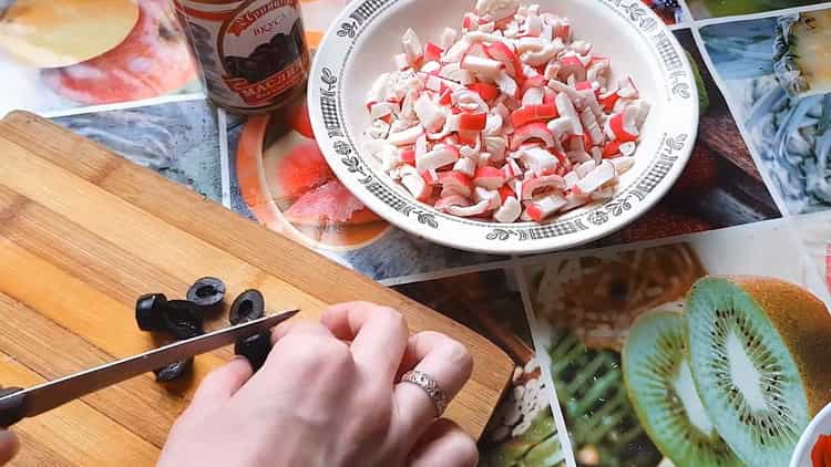 Um Pizza mit Krabbenstäbchen zu machen, hacken Sie Oliven