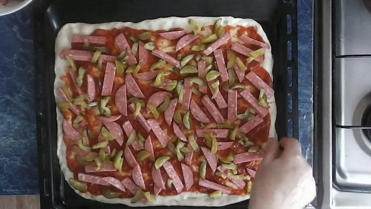 Per fare la pizza con sottaceti, mettere il ripieno sull'impasto