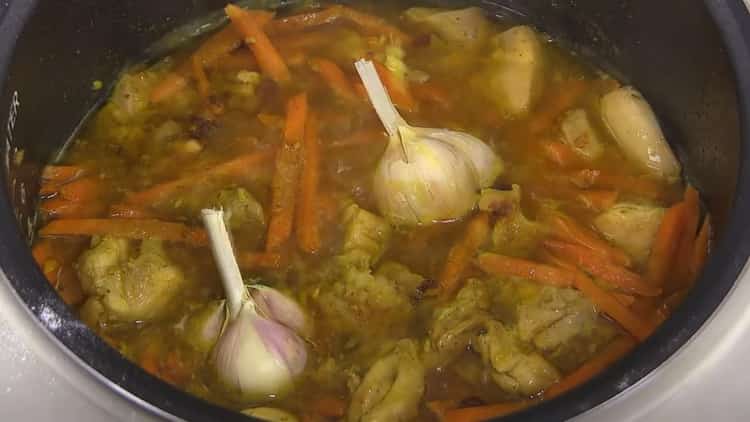 Aggiungi l'aglio per cuocere il pilaf in una pentola a cottura lenta con il pollo