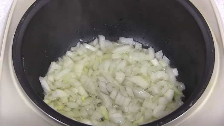 Braten Sie die Zwiebeln, um Pilaw in einem Slow Cooker mit Hühnchen zu kochen