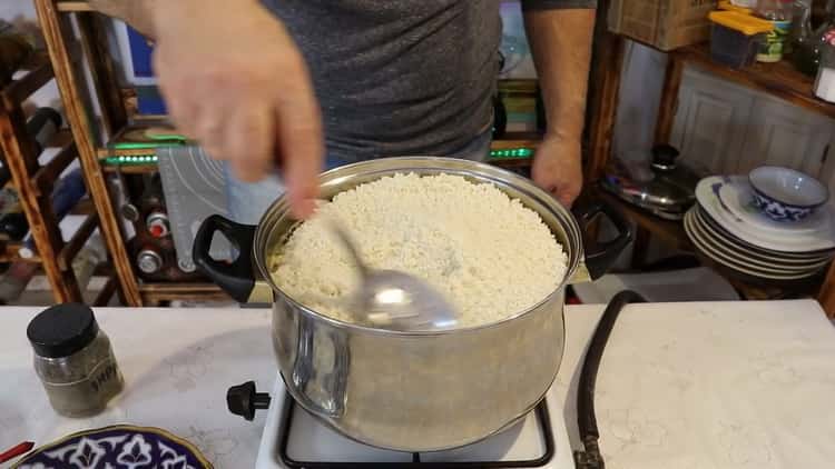 Fügen Sie Reis hinzu, um Schweinepilaf in einer Pfanne zu kochen