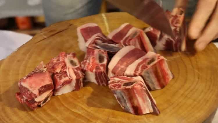 Hacken Sie Fleisch, um Schweinepilaf in einer Pfanne zu kochen
