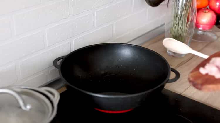 Zum Kochen von Reis mit Gemüse und Hühnchen die Pfanne erhitzen