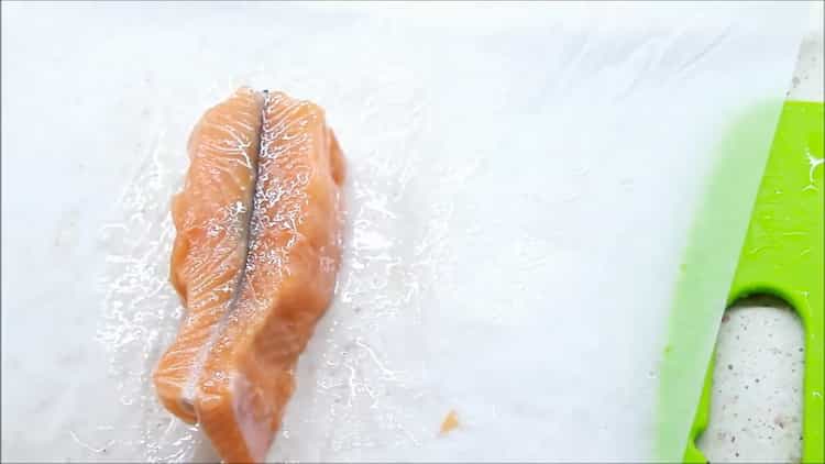 Um Fisch in einer cremigen Sauce zuzubereiten, legen Sie den Fisch auf Pergamentpapier