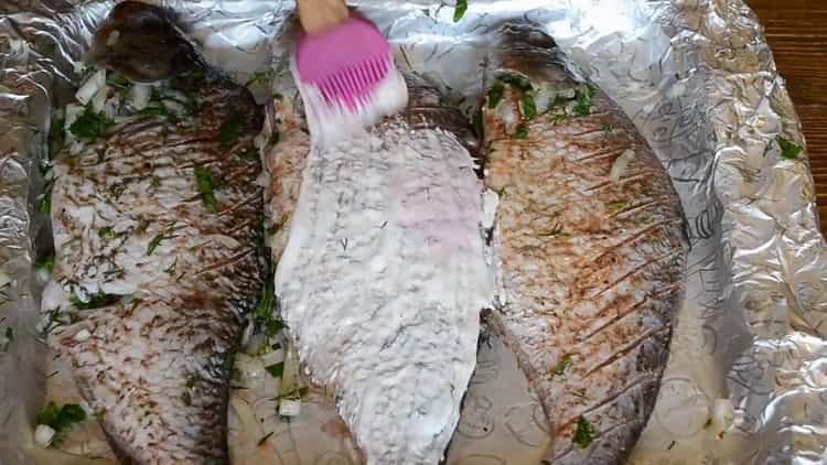 За да готвите риба на заквасена сметана във фурната, намажете рибата със заквасена сметана