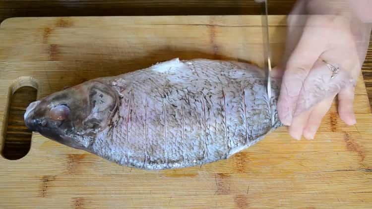 За да готвите риба на заквасена сметана във фурната, направете разрези