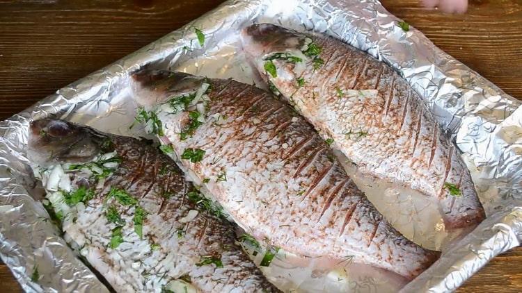 За да готвите риба на заквасена сметана във фурната, сложете съставките в лист за печене
