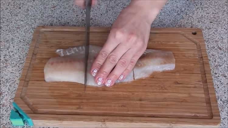 Schneiden Sie den Fisch, um ihn unter einem Pelzmantel im Ofen zuzubereiten