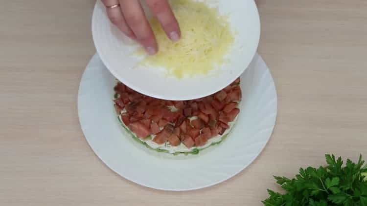 Reiben Sie Käse, um einen Salat mit Avocado und Lachs zuzubereiten