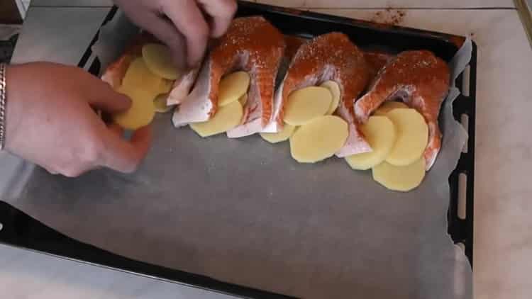 Per cuocere il salmone con le patate al forno, tagliare le patate