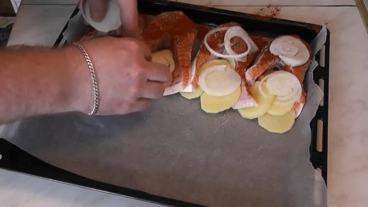 Per cuocere il salmone con le patate al forno, tritare la cipolla