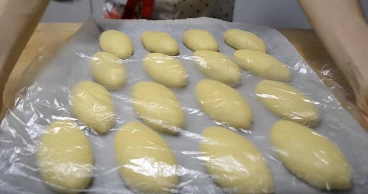 Sinasaklaw namin ang mga buns sa isang baking sheet na may isang pelikula at muling hayaan silang tumayo.
