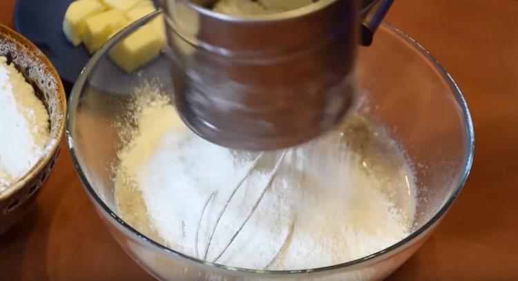 Setacciare la farina sui componenti liquidi.