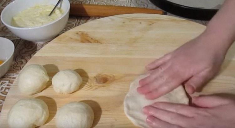 Impastare ogni pallina di pasta in una torta piatta con le mani.