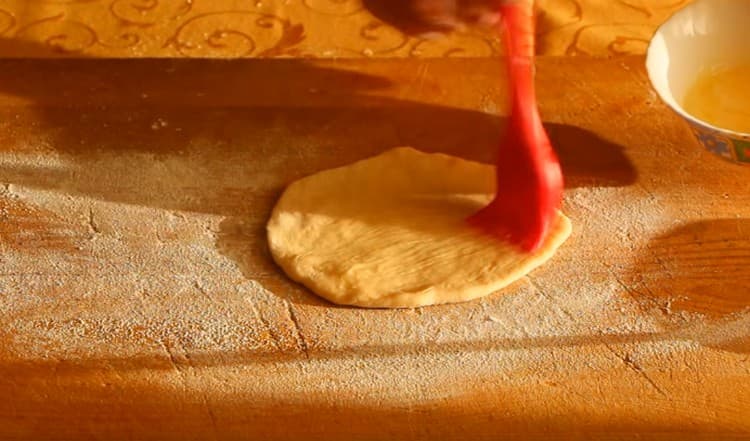 Arrotolare una fetta di pasta in una torta e ungerla con burro fuso.