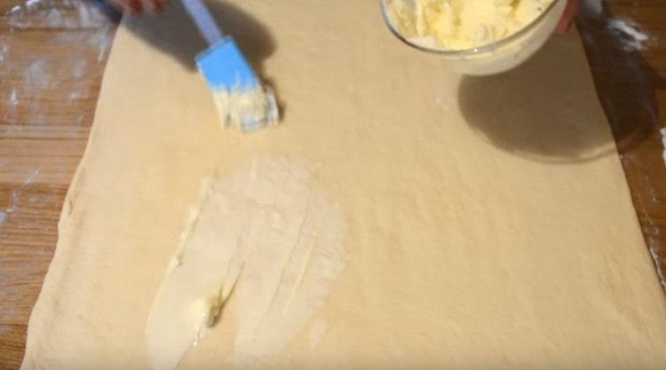 Die Teigschicht mit weicher Butter schmieren.